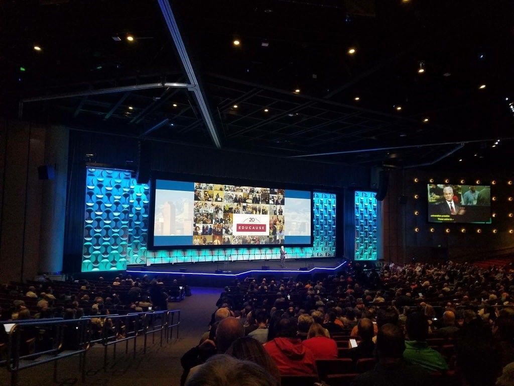 A large auditorium filled with people watching a presentation