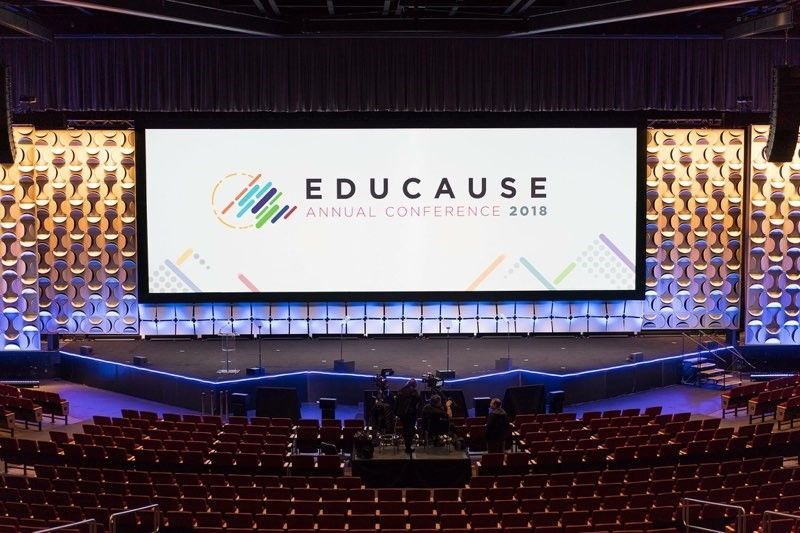 An empty auditorium with a large screen that says educate on it.