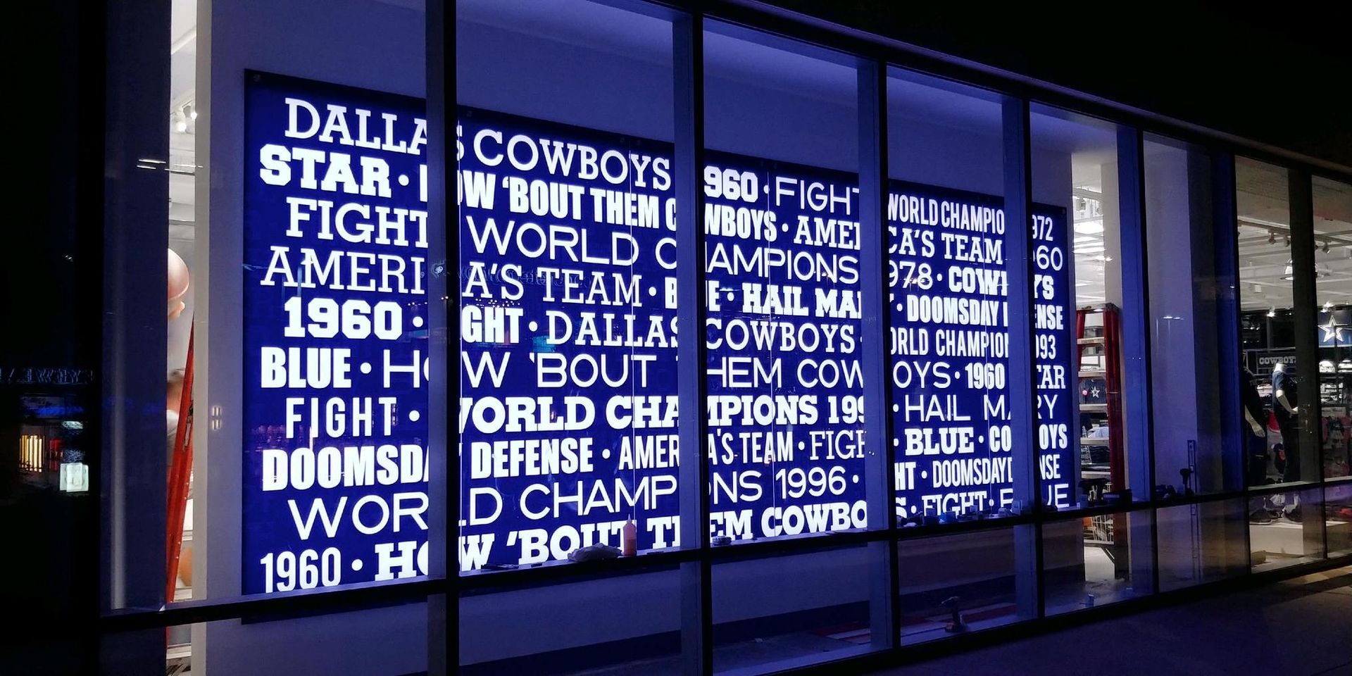 Large illuminated sign outside, blue text on white. Mentions Dallas Cowboys, America's team, and Super Bowl wins.