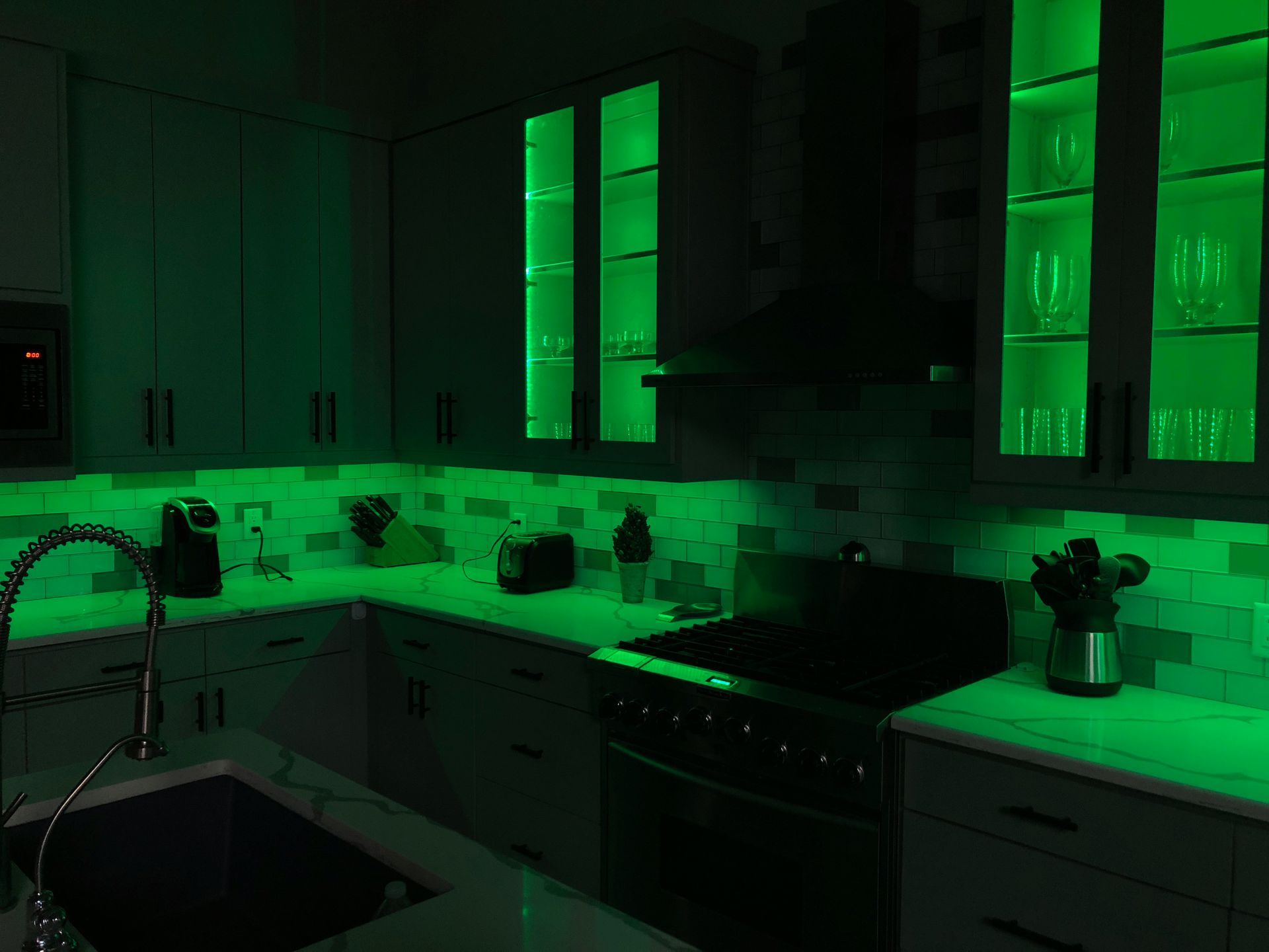 A kitchen with green lights on the cabinets and counter tops.