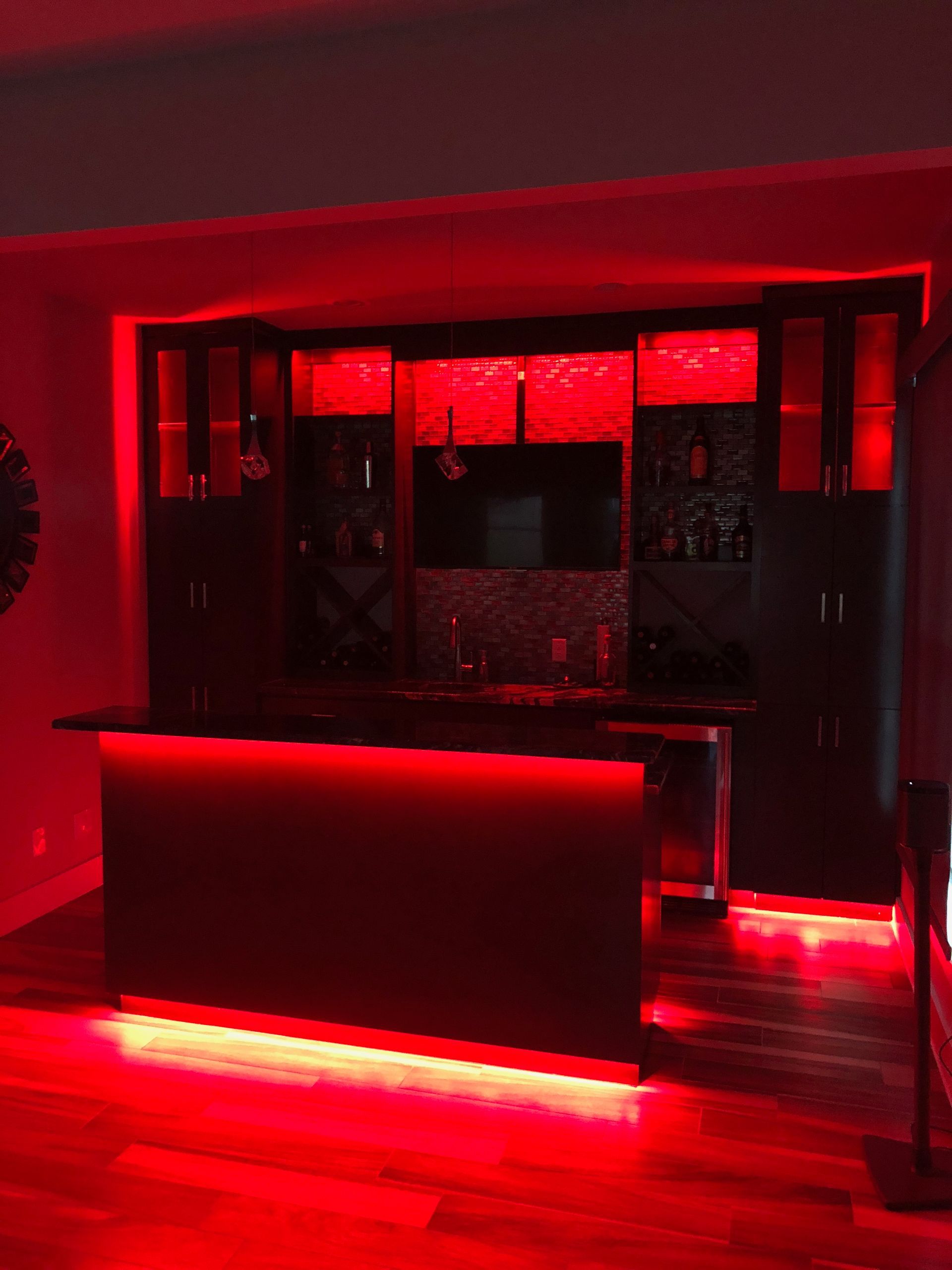 A kitchen with red lights on the walls and a bar.