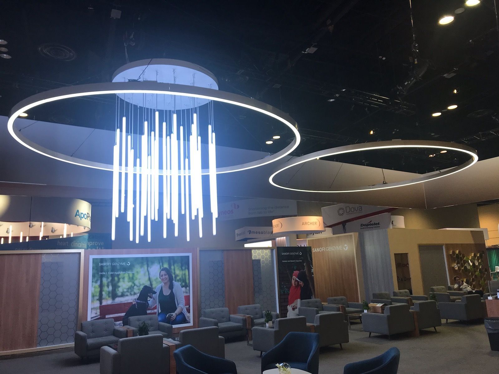 Modern seating area with circular LED light fixtures hanging from a dark ceiling.