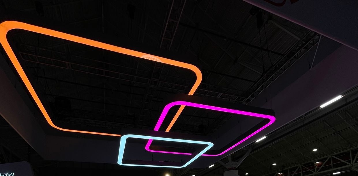 Neon-colored square light fixtures on a dark ceiling. Orange, pink, and blue lights overlap.