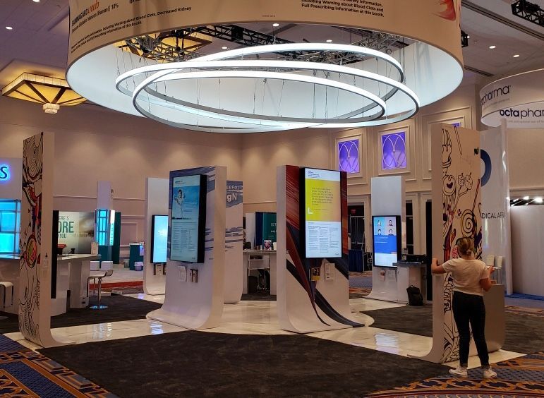 A woman is standing in a room with a lot of screens on the wall.