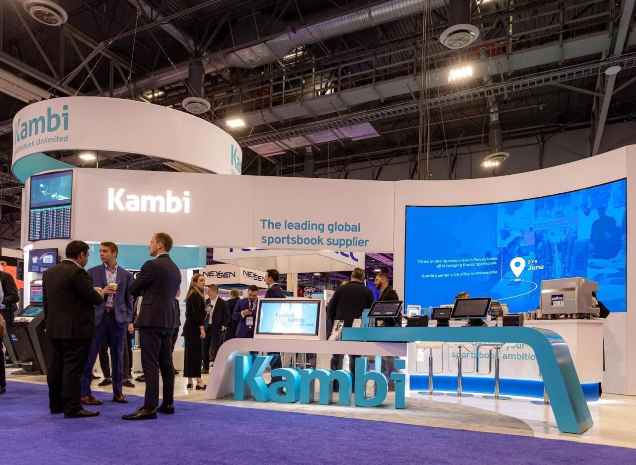 A group of people are standing around a booth at a convention.