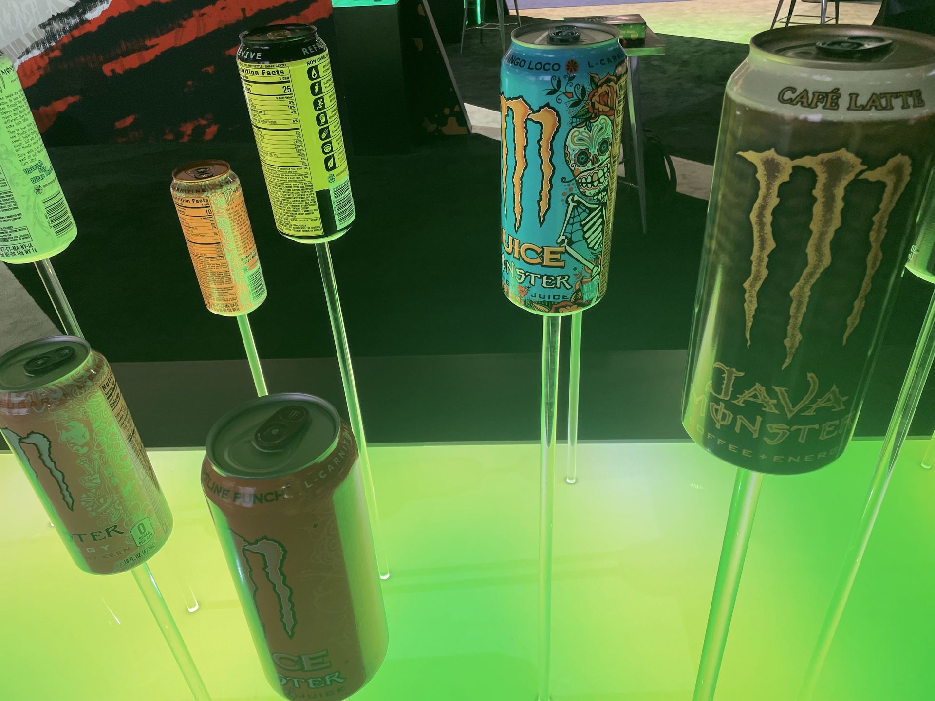Several cans of monster energy drinks are on display above green LED