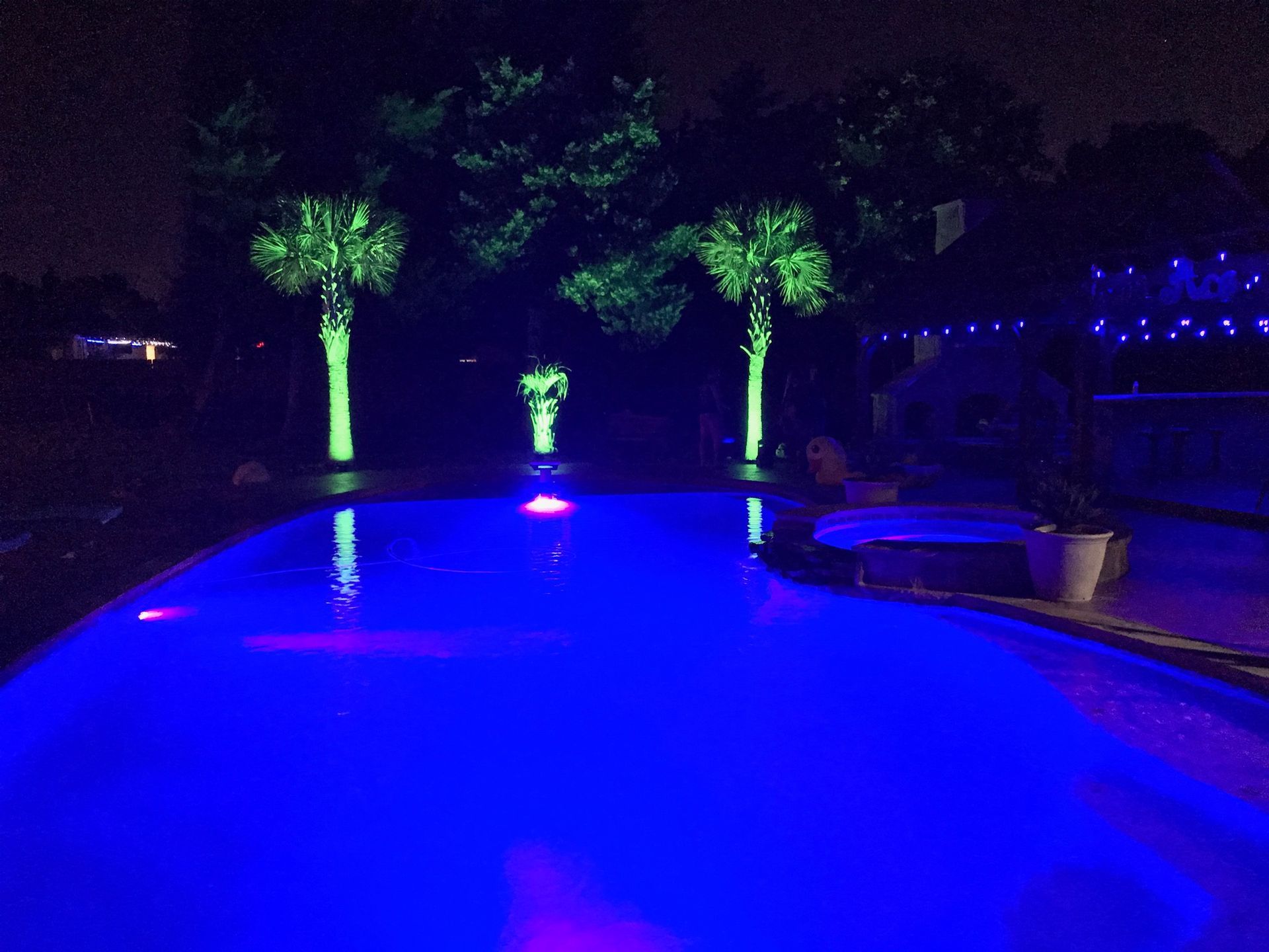 A swimming pool is lit up with blue lights at night.