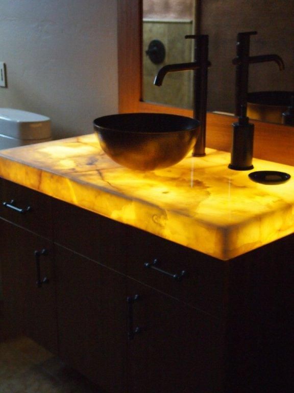A bathroom sink with a lighted counter top