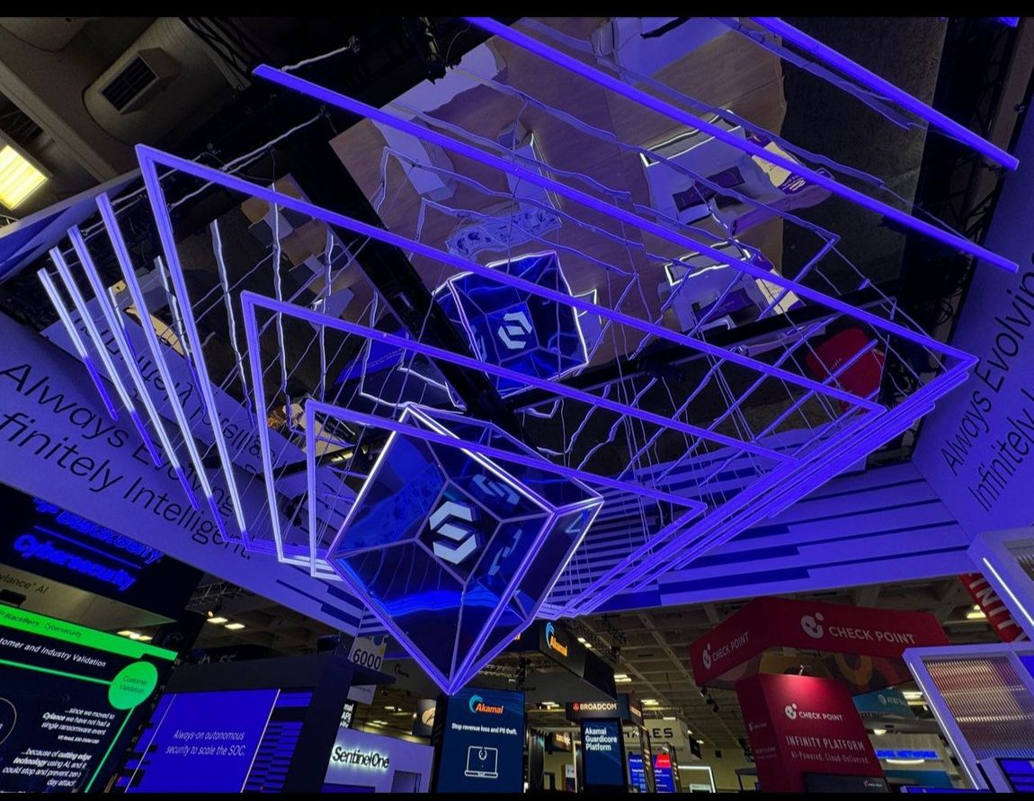 Blue-lit geometric display hanging from a ceiling. Several cube-shaped elements with logos are suspended in the air.