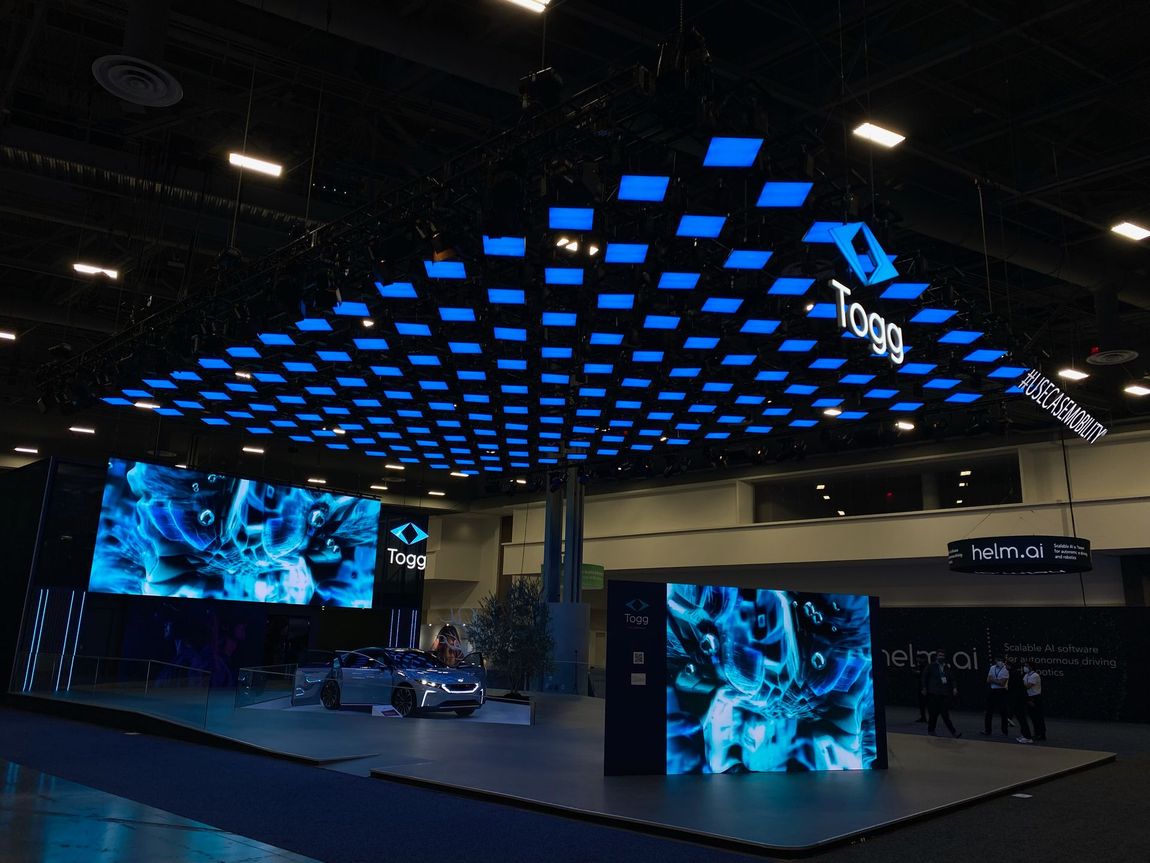 A car display at an exhibition with blue screens and a Togg logo.