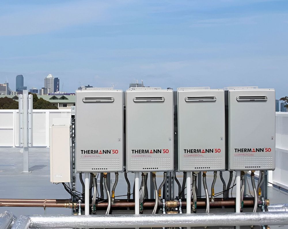 Four Grey Thermann 50 Water Heaters on a Rooftop and Pipes Visible — Corrimal Plumbing Services in Shellharbour, NSW