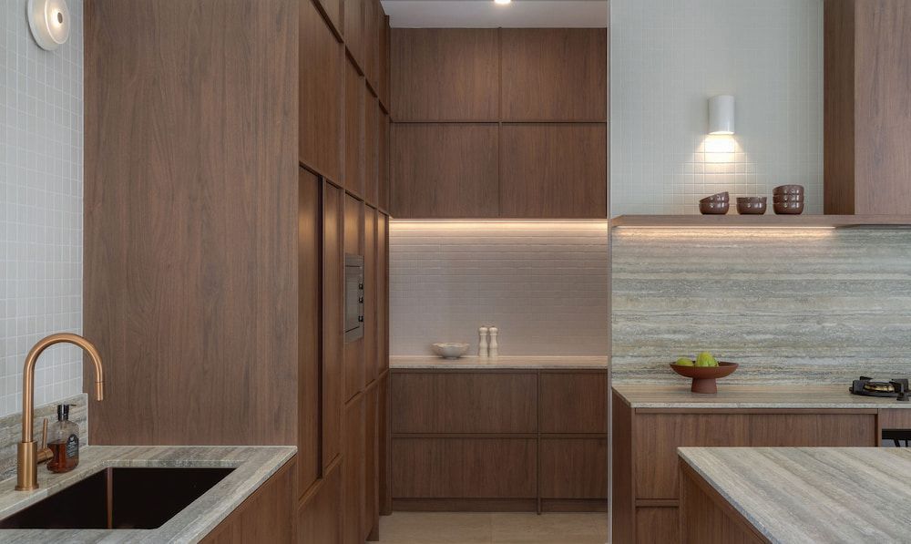 Modern Kitchen With Brown Wood Cabinets and Marble Countertops — Corrimal Plumbing Services in East Corrimal, NSW