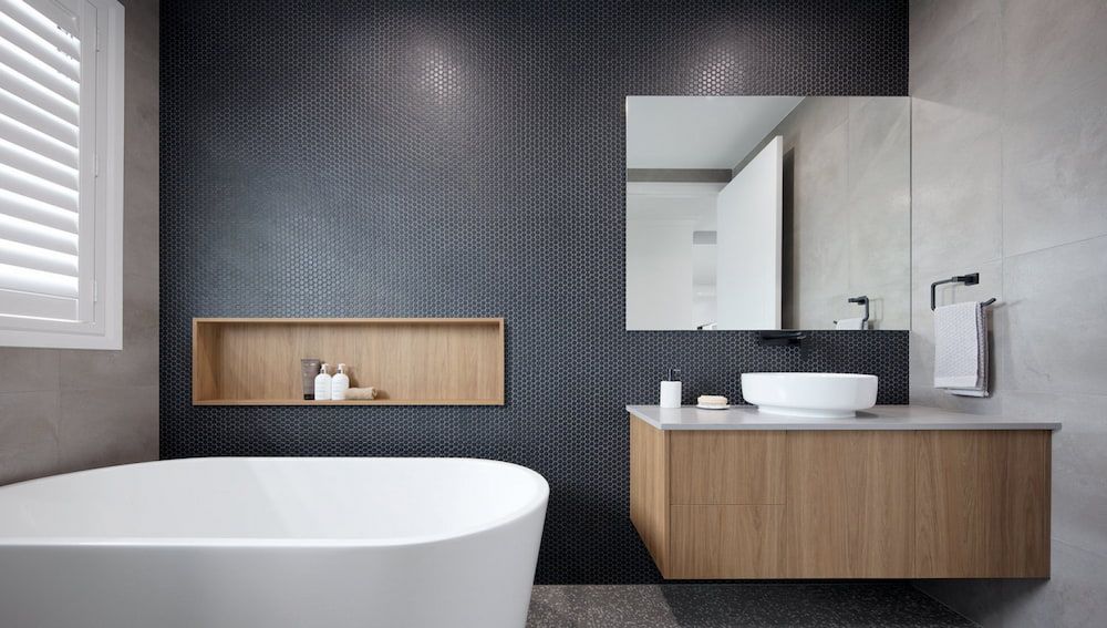 Modern Bathroom With a Bathtub, Wooden Vanity, and Textured Dark Blue Wall — Corrimal Plumbing Services in East Corrimal, NSW