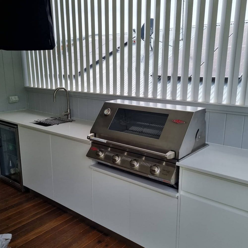 Outdoor Kitchen With Stainless Steel Grill, Sink and White Cabinets — Corrimal Plumbing Services in East Corrimal, NSW