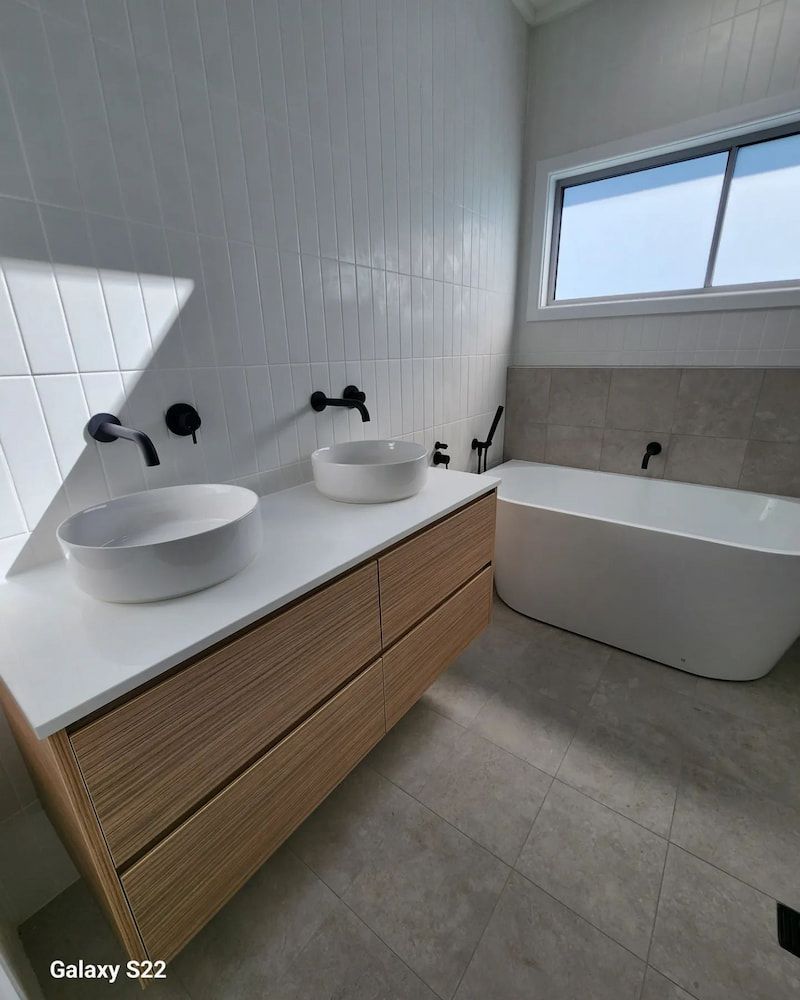 Modern Bathroom With White Walls, Wood Vanity and Vessel Sinks — Corrimal Plumbing Services in Shellharbour, NSW