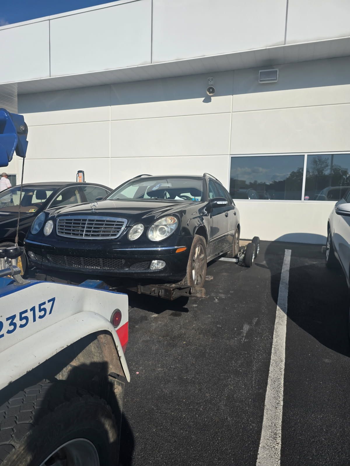 A car is being towed by a tow truck with the number 235157 on it