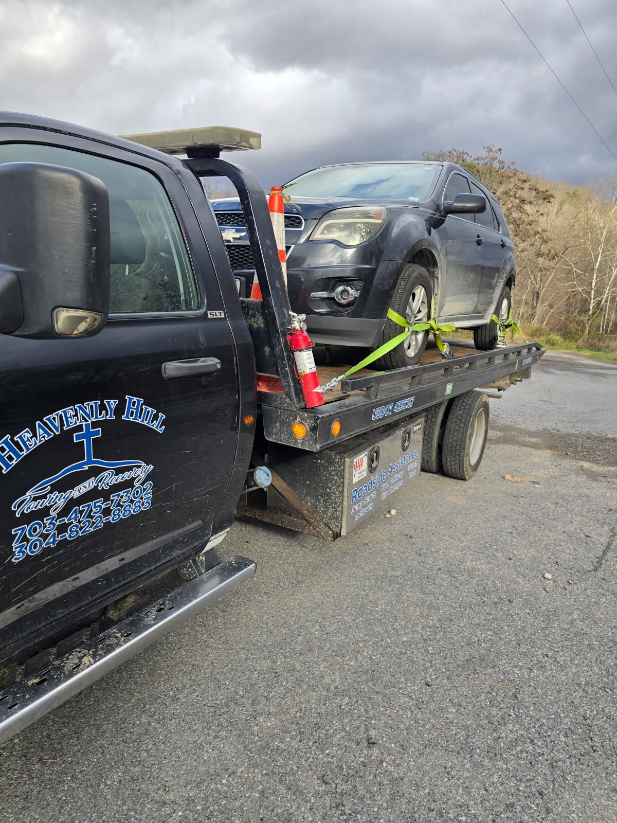 A tow truck is towing a car on the back of it.