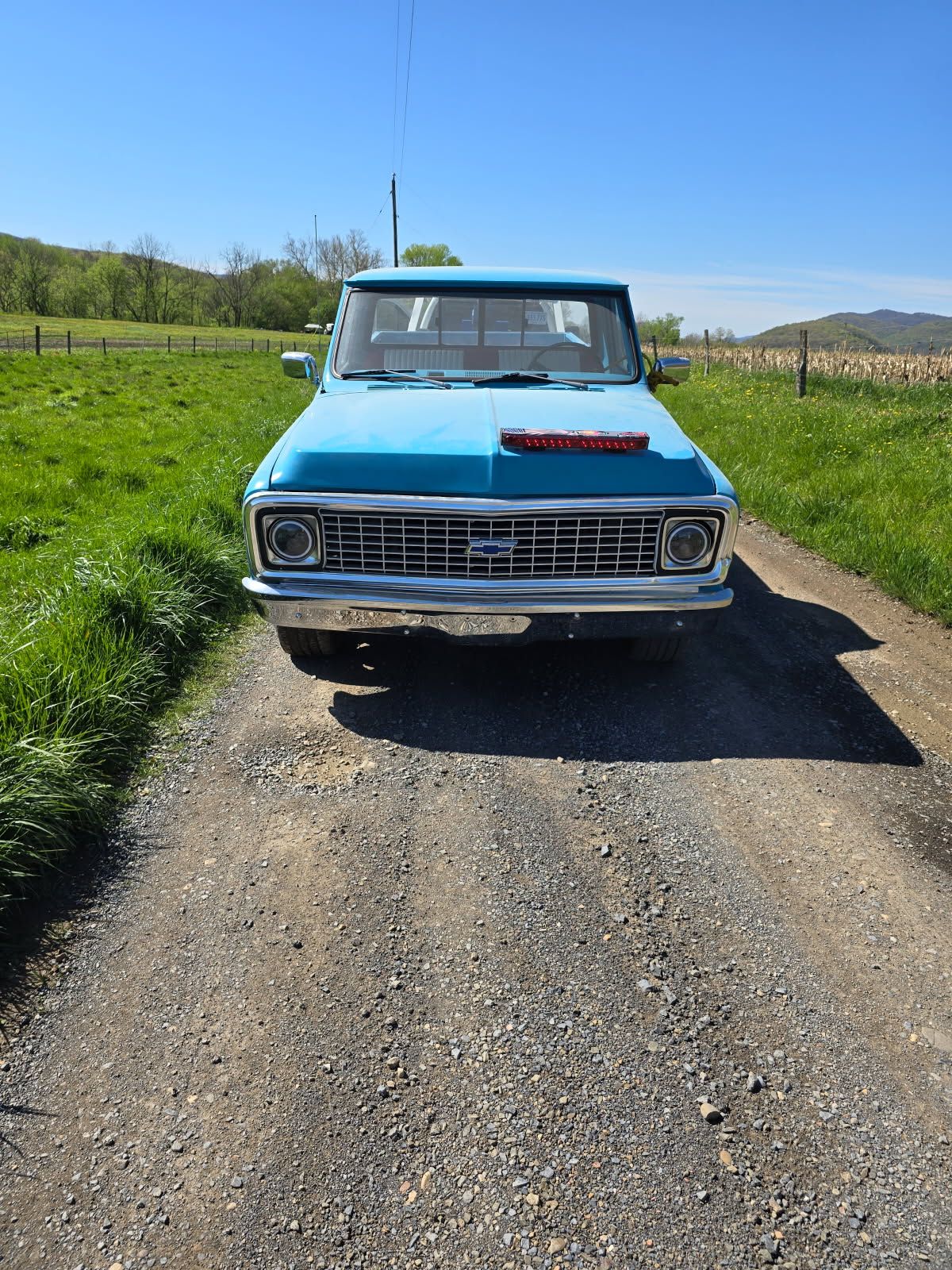 A blue truck is parked on the side of a dirt road.