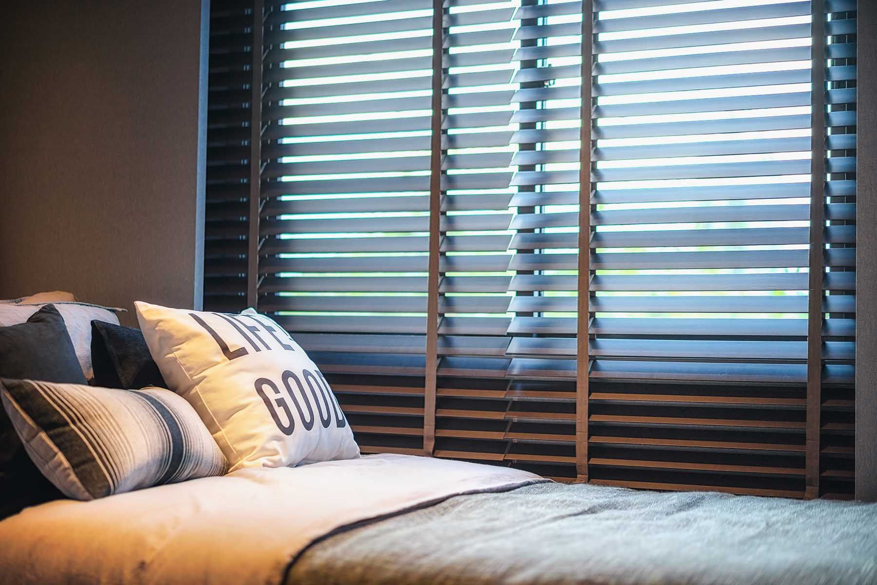 Bed with pillows and wooden blinds in a bedroom.