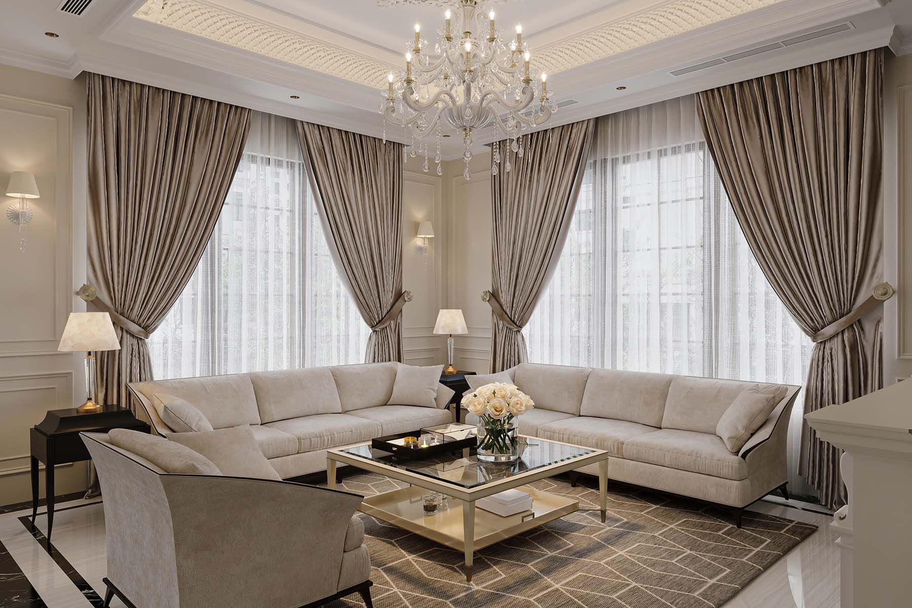 Elegant living room with beige sofas, patterned rug, sheer curtains, and a chandelier.