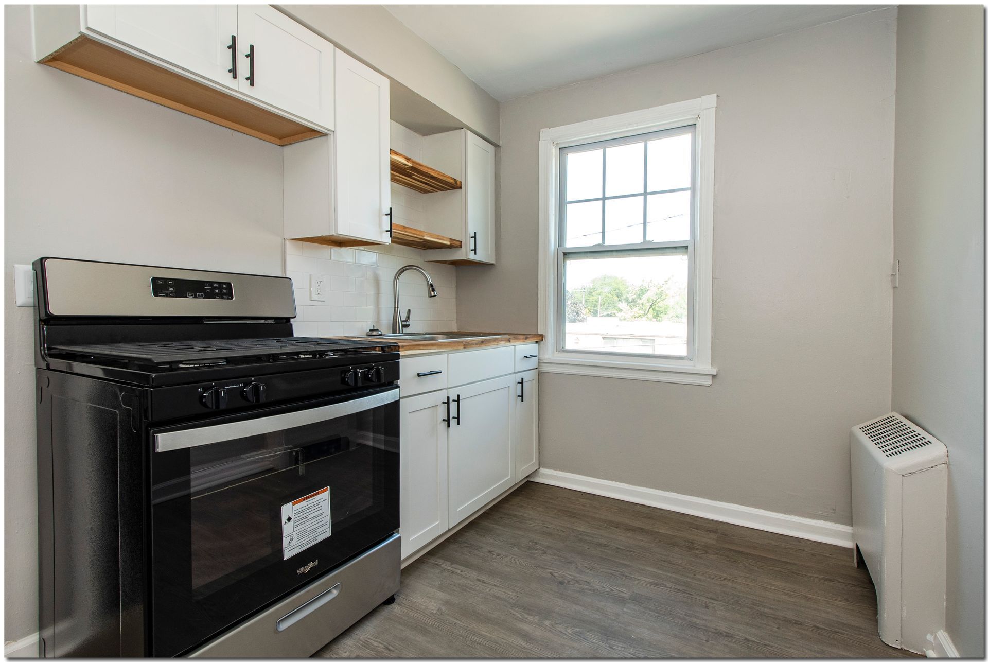 Small kitchen with white cabinets, stainless steel appliances, and a window.