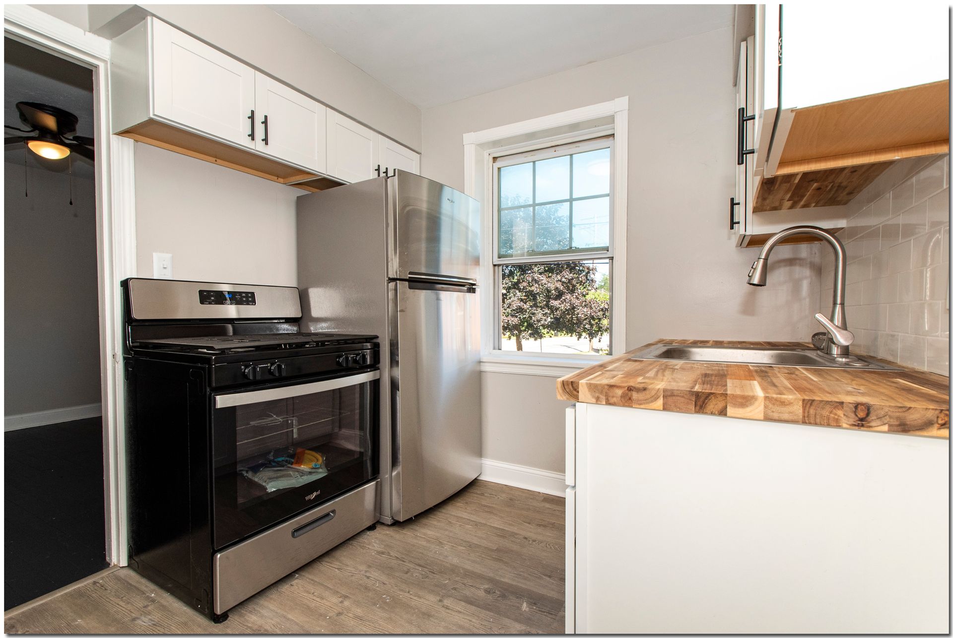 Small kitchen with stainless steel appliances, white cabinets, and butcher block countertops.