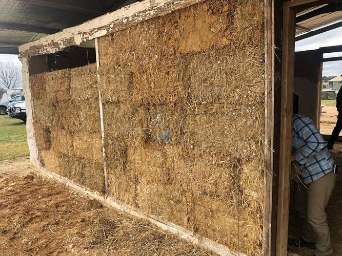 A Man Is Standing In Front Of A Wall Made Of Hay Bales — Green e Building in Lennox Head, NSW