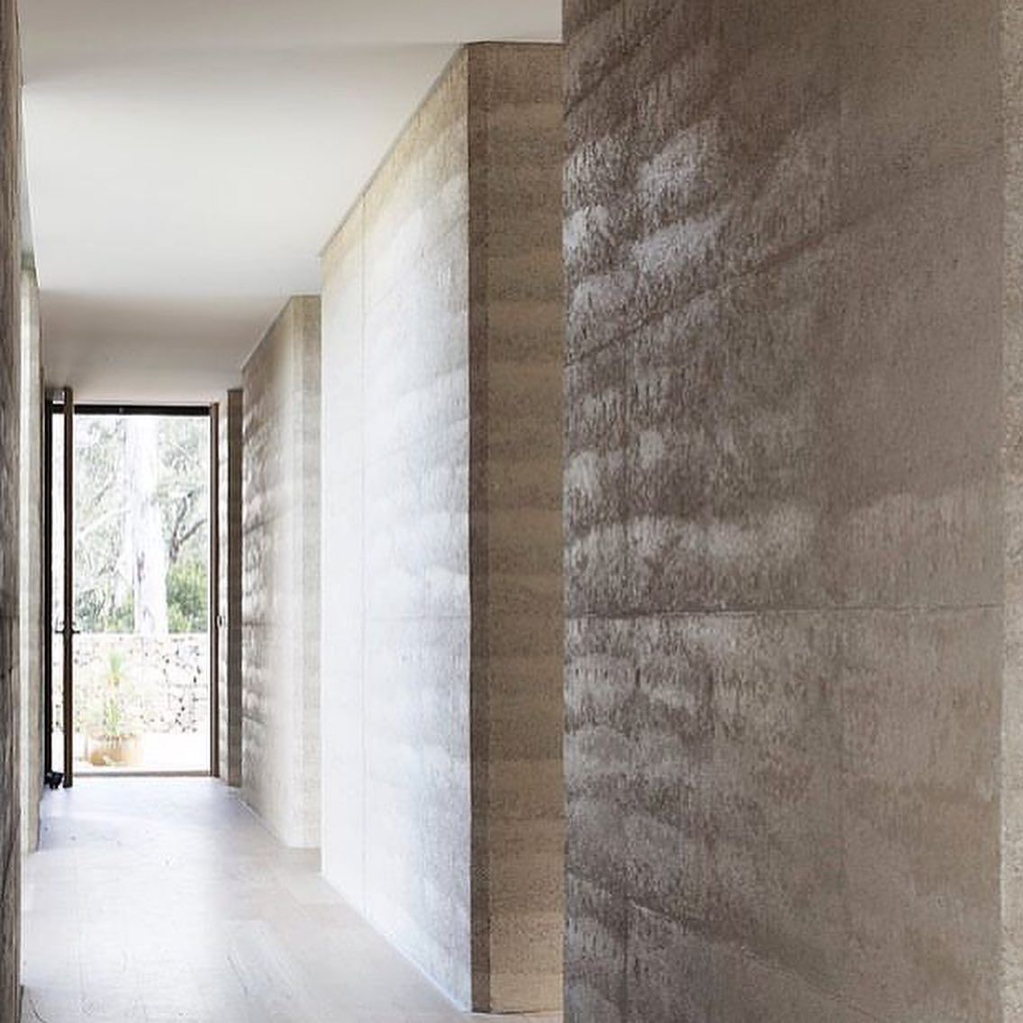 A Long Hallway With Rammed Earth Walls And A Door — Green e Building in Lennox Head, NSW
