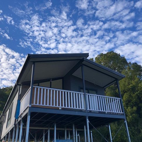 A House On Stilts With A Balcony And A Blue Sky In The Background  — Green e Building in Lennox Head, NSW