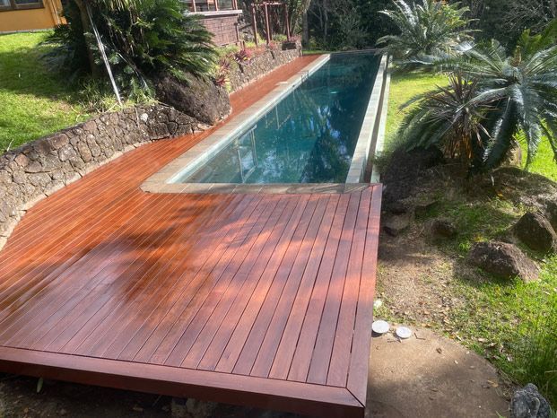 A Wooden Deck Next To A Swimming Pool In A Garden — Green e Building in Lennox Head, NSW