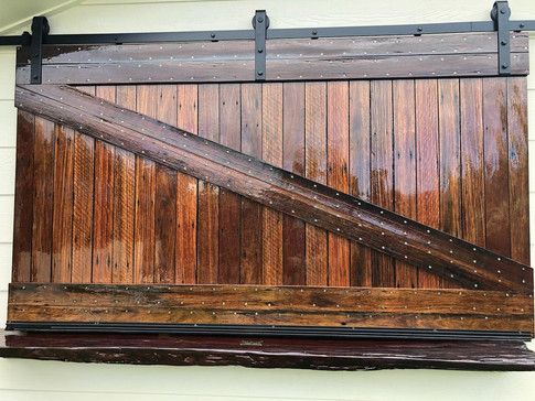 A Wooden Sliding Barn Door on A White Wall  — Green e Building in Lennox Head, NSW