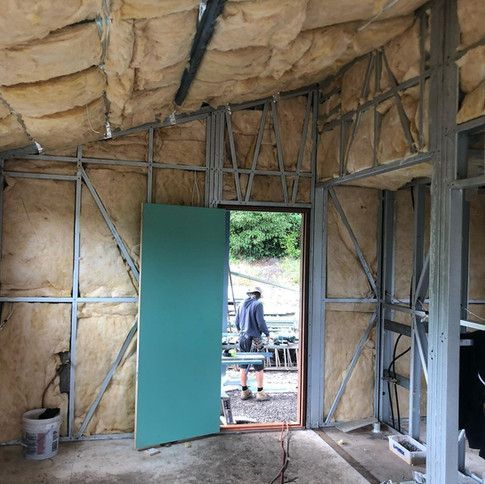 A Man Is Standing In A Room With A Green Door — Green e Building in Lennox Head, NSW