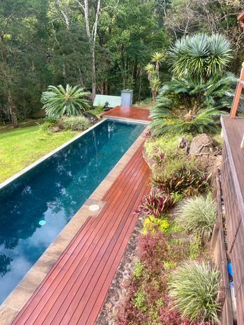 A Large Swimming Pool Surrounded By Trees And A Wooden Deck — Green e Building in Lennox Head, NSW