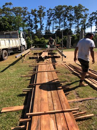 A Man Is Cutting Wood with A Circular Saw in A Field — Green e Building in Lennox Head, NSW