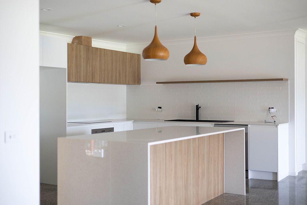 A Kitchen With White Cabinets And A Wooden Island — Green e Building in Lennox Head, NSW