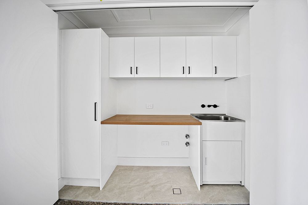 An Empty Kitchen With White Cabinets And A Wooden Counter Top — Green e Building in Yamba, NSW