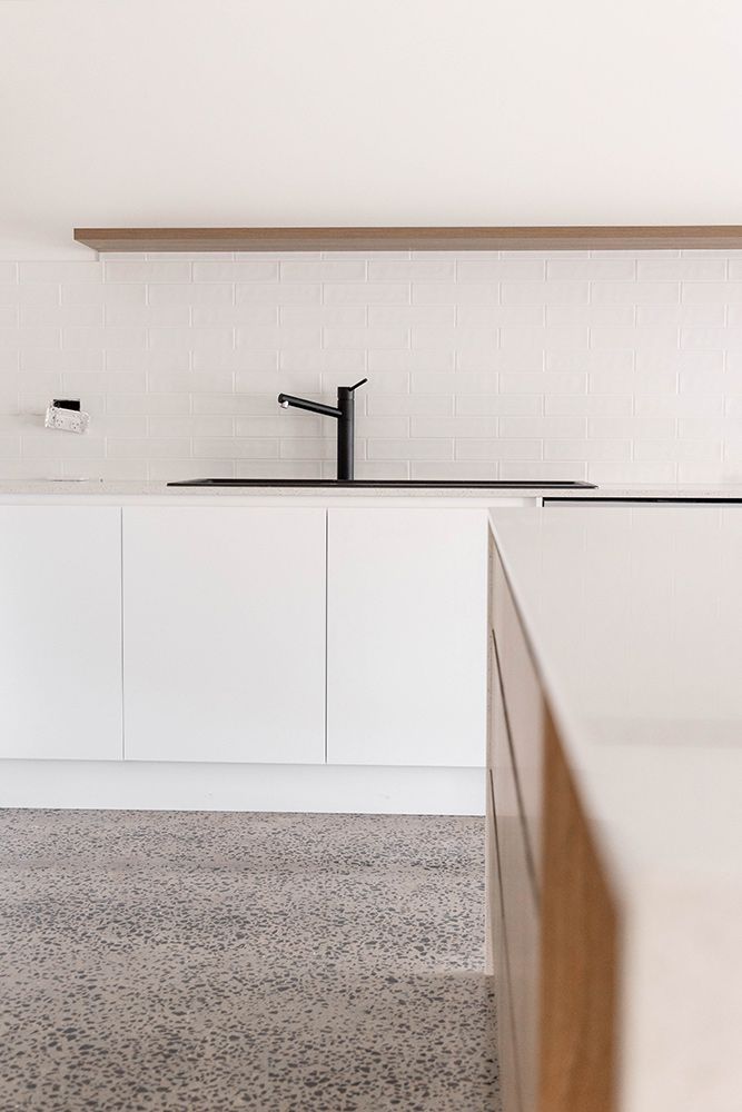 A Kitchen With White Cabinets And A Black Sink — Green e Building in Yamba, NSW