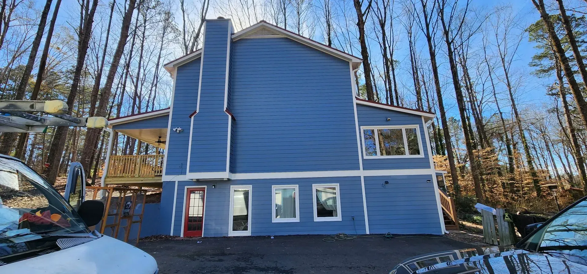 Blue house with a chimney in a wooded area on a sunny day.