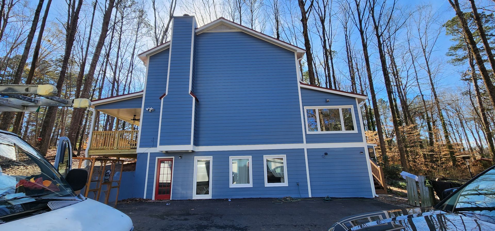 Blue house in a snowy forest, with a chimney.