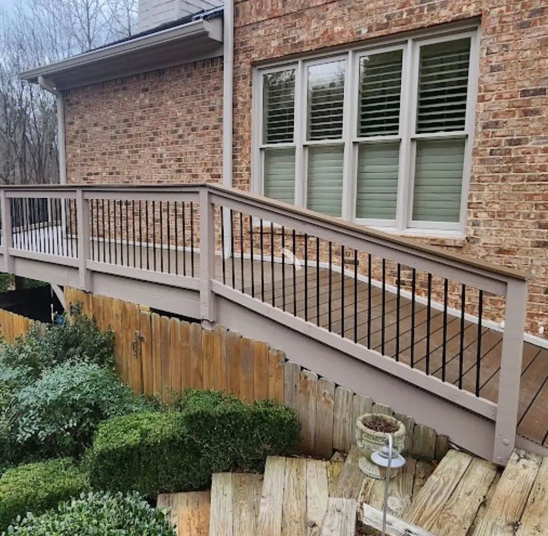 A wooden deck with a handrail on a brick house. Steps lead to the deck.