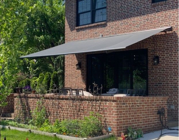 White retractable awning with pleated fabric suspended from a metal track.