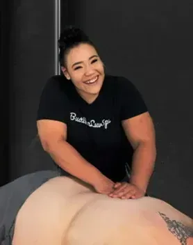 A woman in a black shirt is smiling while giving a massage to a man.