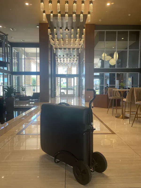 A black suitcase is on a cart in a lobby