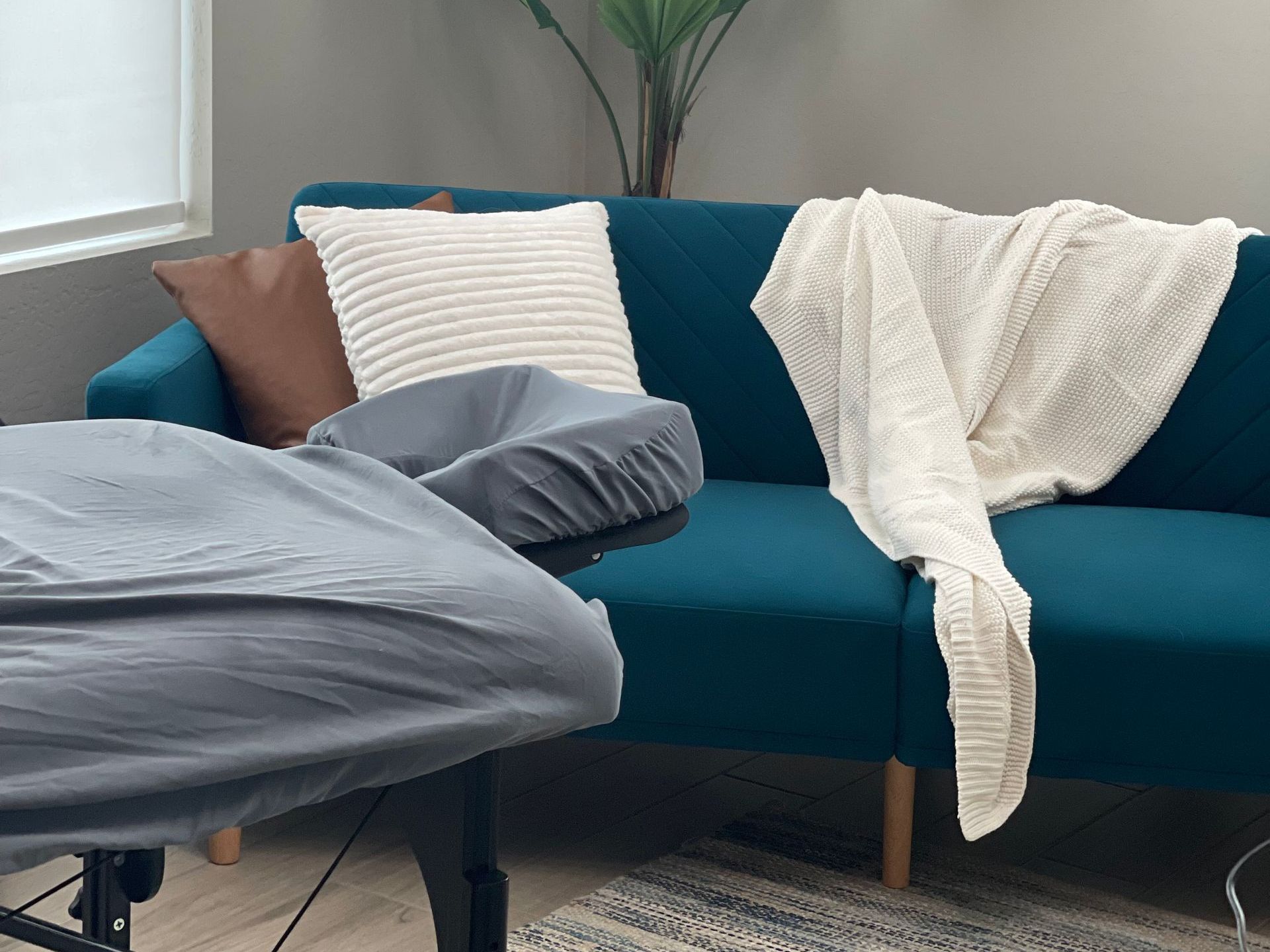 A blue couch with pillows and a blanket on it