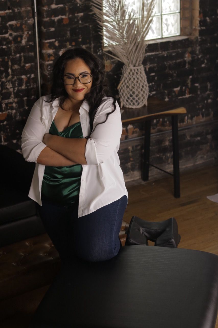 A woman is kneeling on a table with her arms crossed.