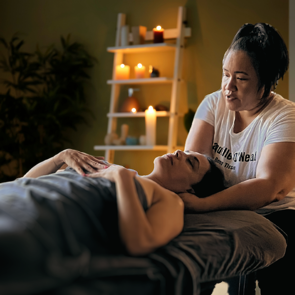 A woman is giving a massage to another woman who is laying on a bed