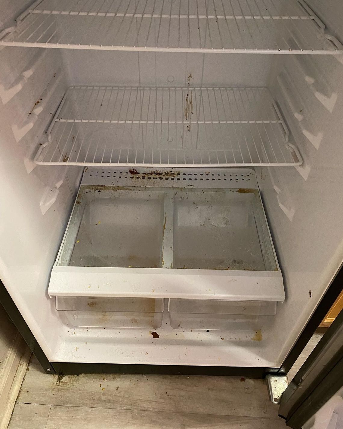 The inside of an empty refrigerator with dirty drawers and shelves.