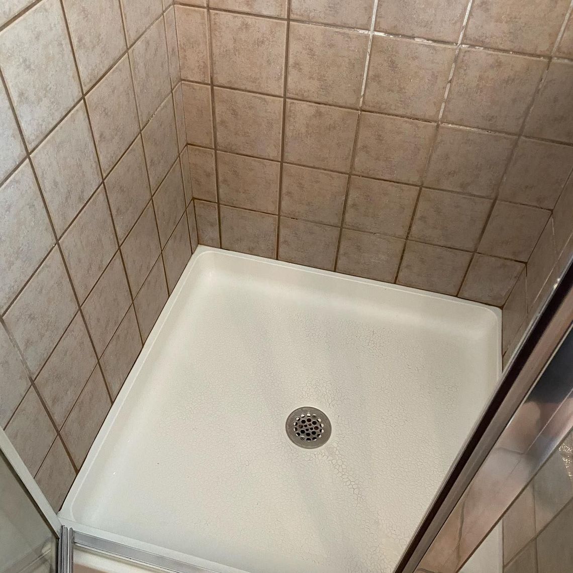 A shower stall with a drain in the middle of it