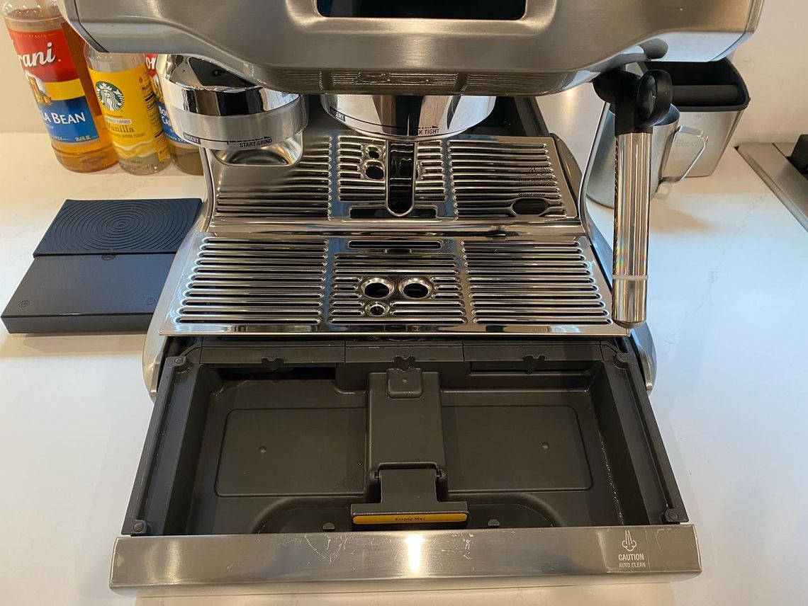 A coffee machine is sitting on a counter with the lid open.