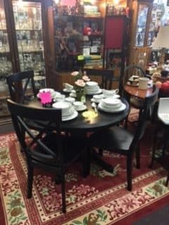 A dining room with a table and chairs and plates on it.